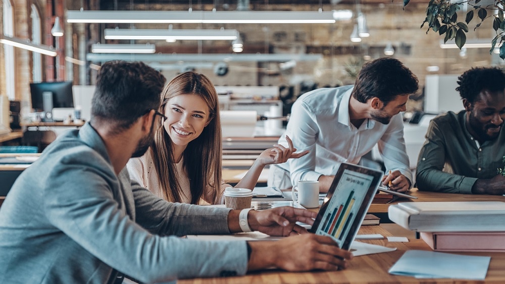 Four people in office discussing digital strategy at a meeting table