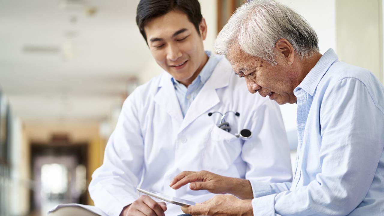 Professionnel de la santé aidant un patient à utiliser une tablette Professionnel de la santé aidant un patient à utiliser une tablette