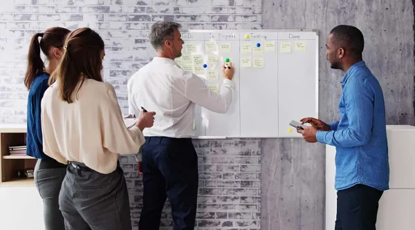 Four diverse professionals agile planning on a whiteboard