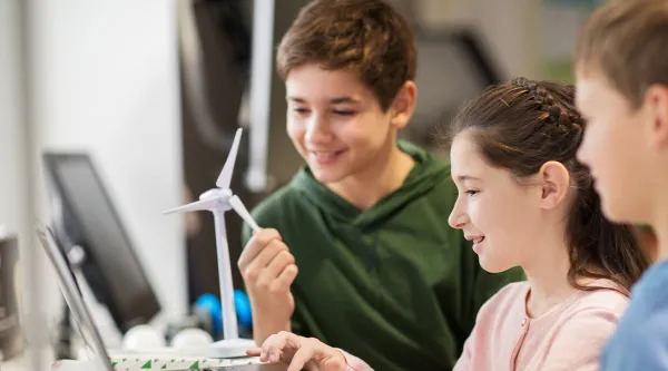 three children playing with laptop and smiling